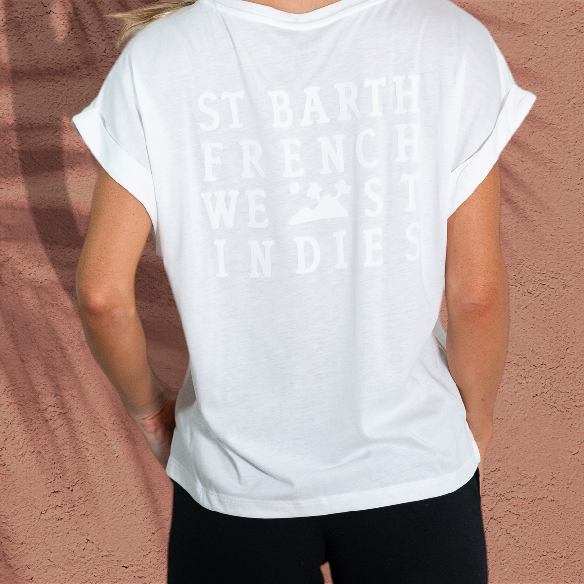 Femme portant le t-shirt blanc Maria St Barth French West Indies avec logo en velours au dos et manches retroussées