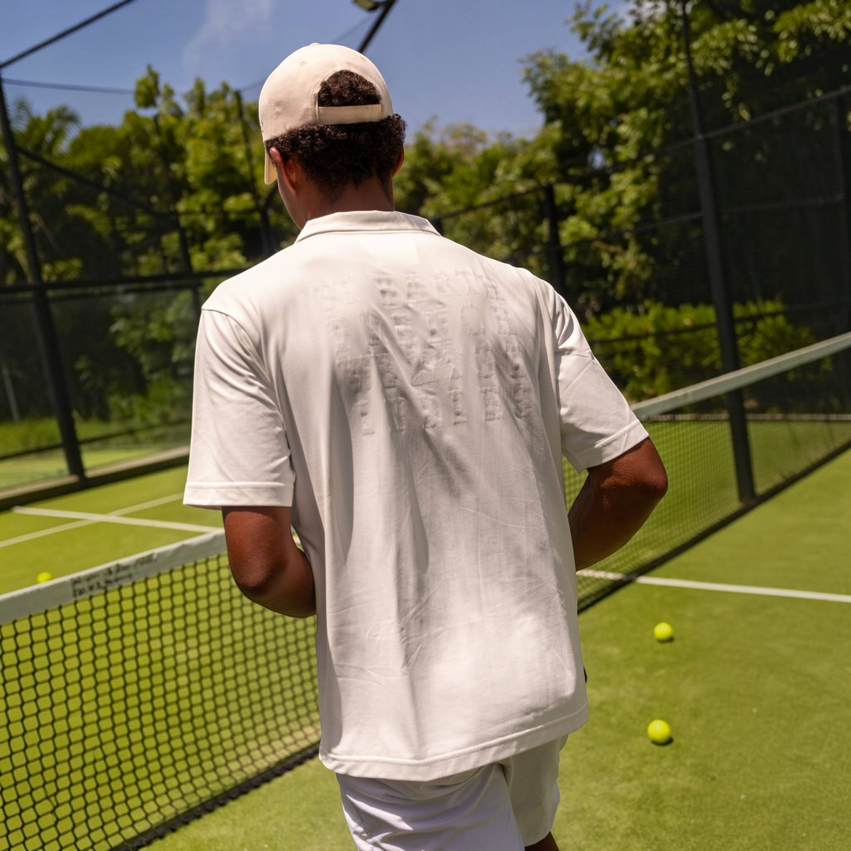Homme portant le polo blanc St Barth French West Indies respirant avec protection UV sur un terrain de padel