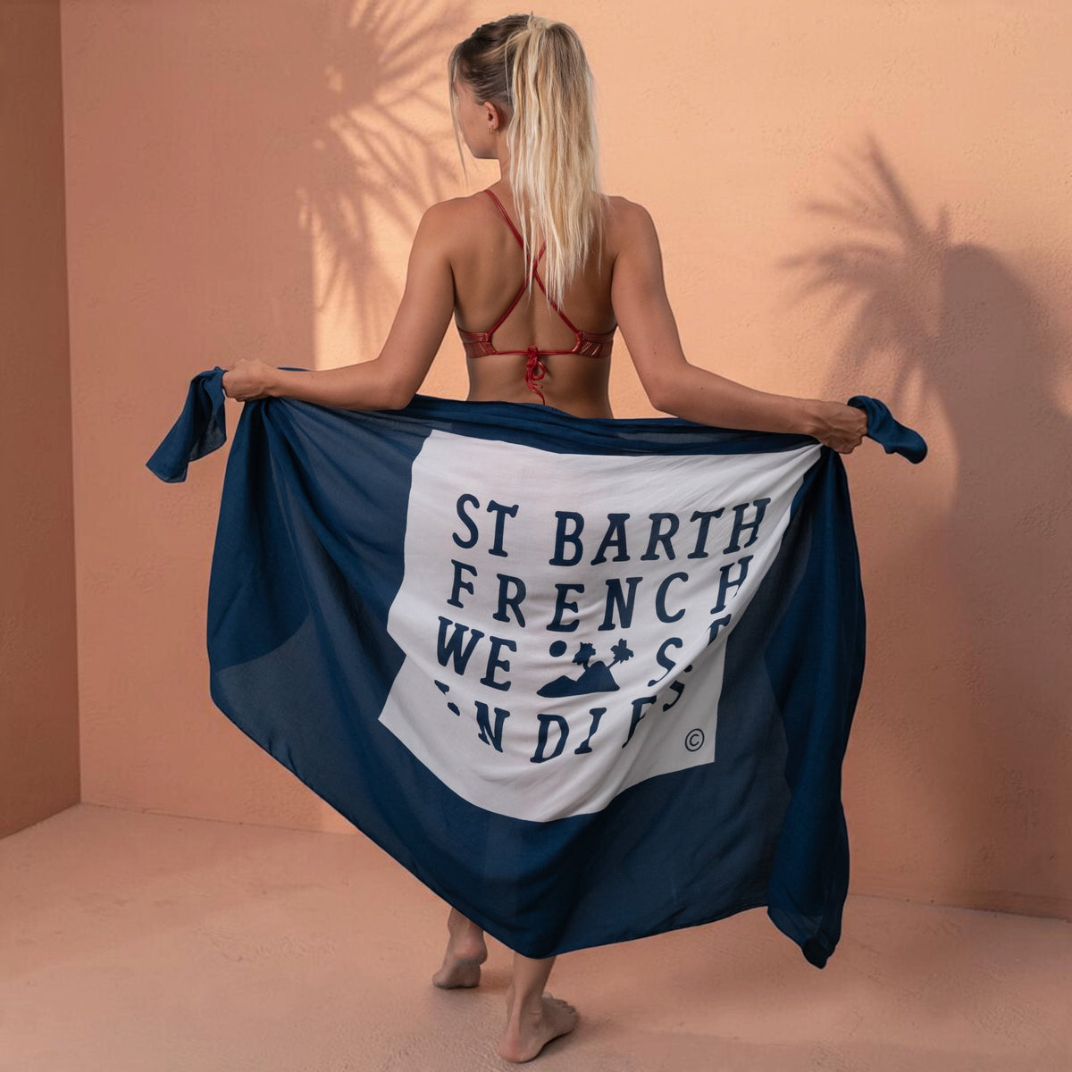 Femme portant un paréo St Barth French West Indies en voile de rayonne bleu marine avec logo blanc au dos