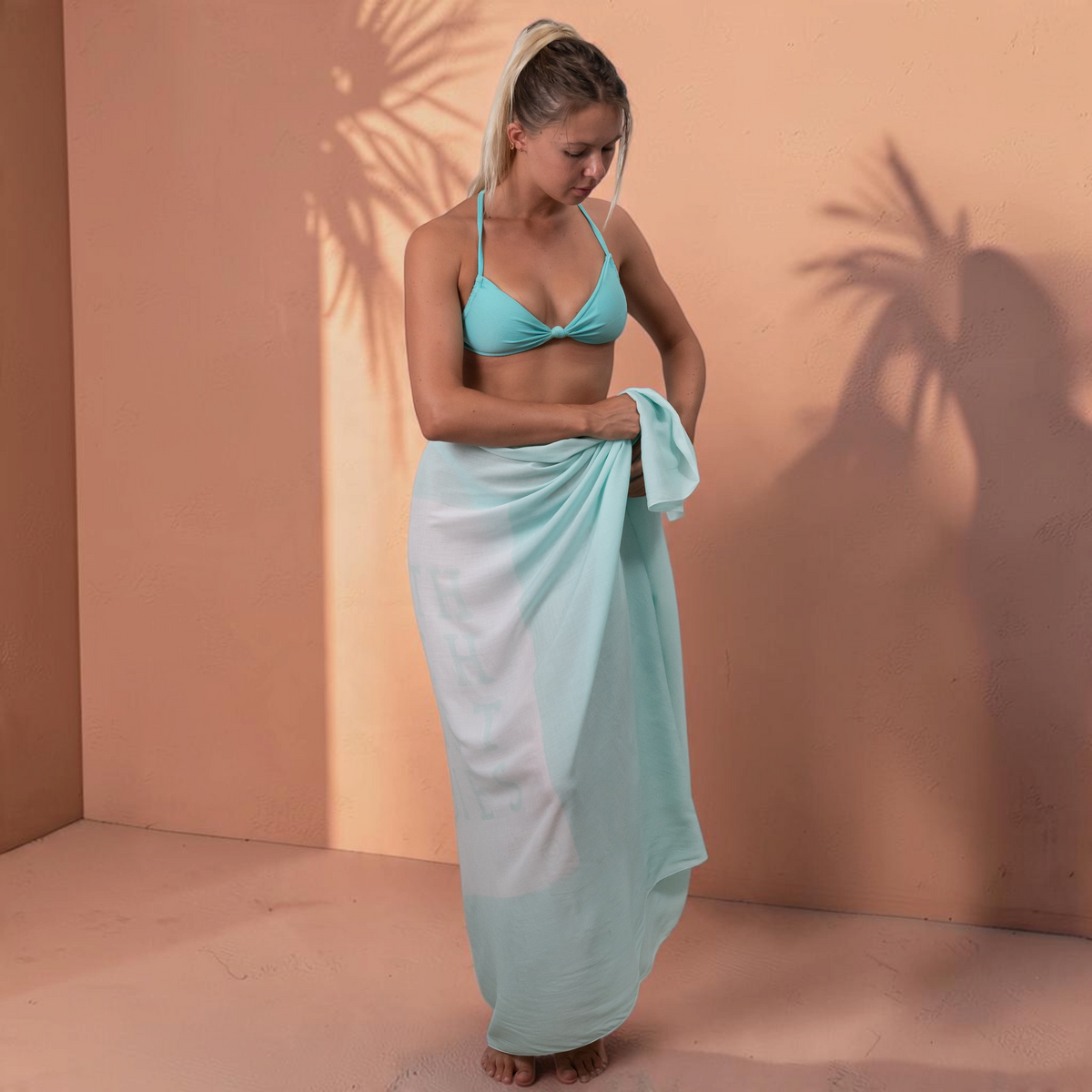 Femme portant un paréo St Barth French West Indies en voile de rayonne bleu clair noué à la taille sur un bikini
