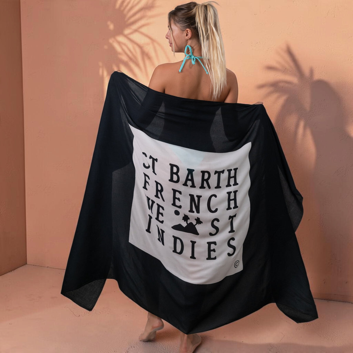 Femme portant un paréo St Barth French West Indies en voile de rayonne noir avec logo blanc au dos