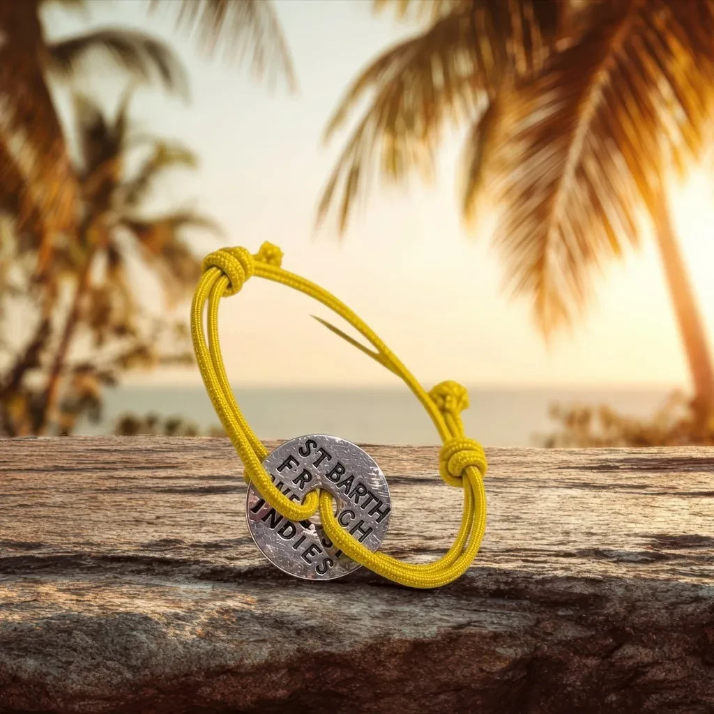 Bracelet St Barth French West Indies jaune avec cordon Γ©lastique et mΓ©daille en mΓ©tal gravΓ©e sur fond tropical