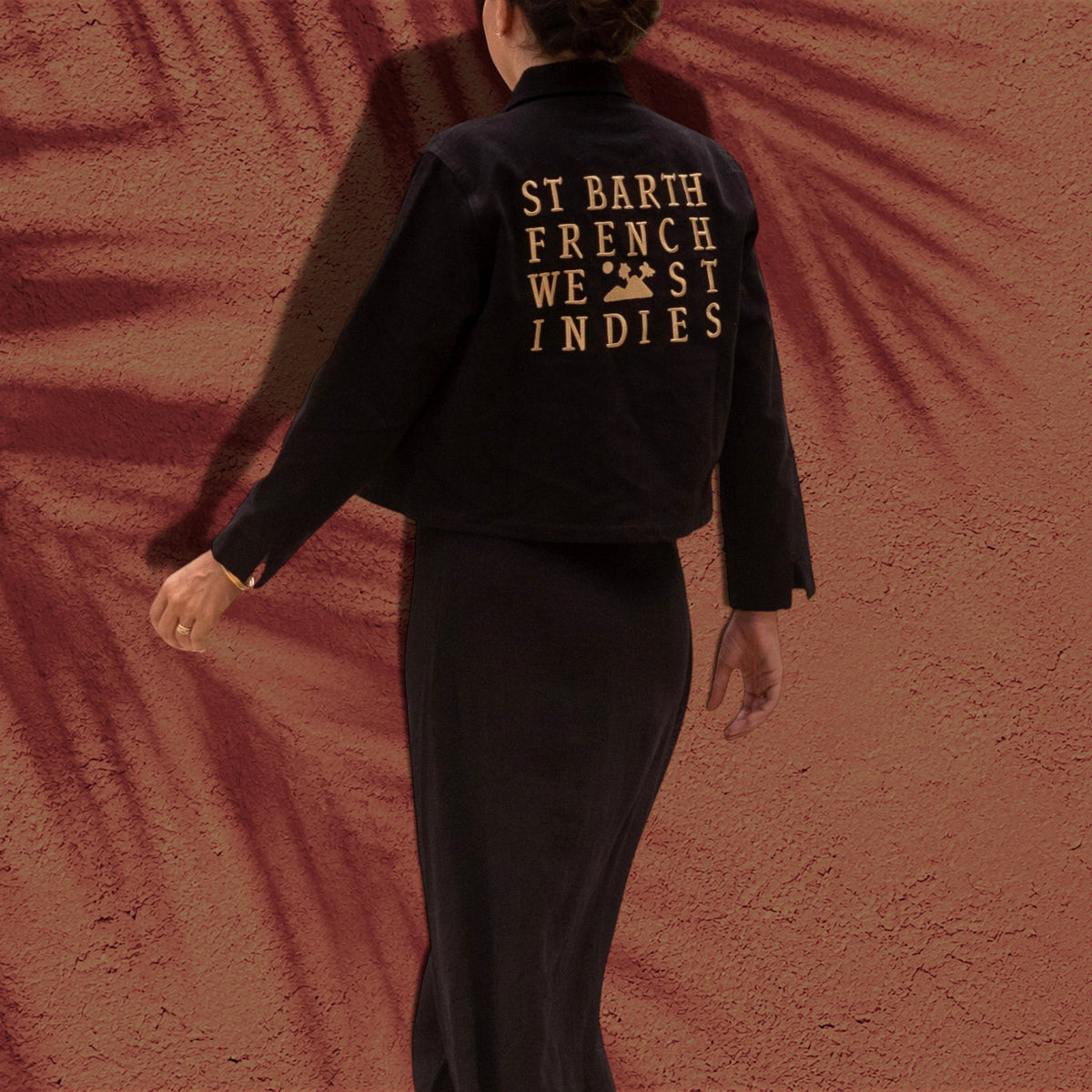 Veste courte noire St Barth French West Indies en sergé de coton avec broderie dorée au dos sur fond texturé