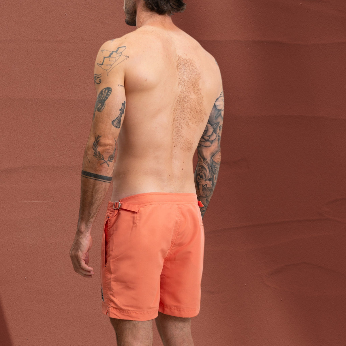 Homme portant un short de bain St Barth French West Indies orange avec ajusteurs latéraux chromés, vue de dos