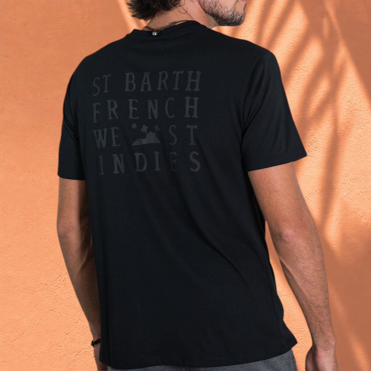 Homme portant le t-shirt noir Gustave St Barth French West Indies avec logo ton sur ton au dos
