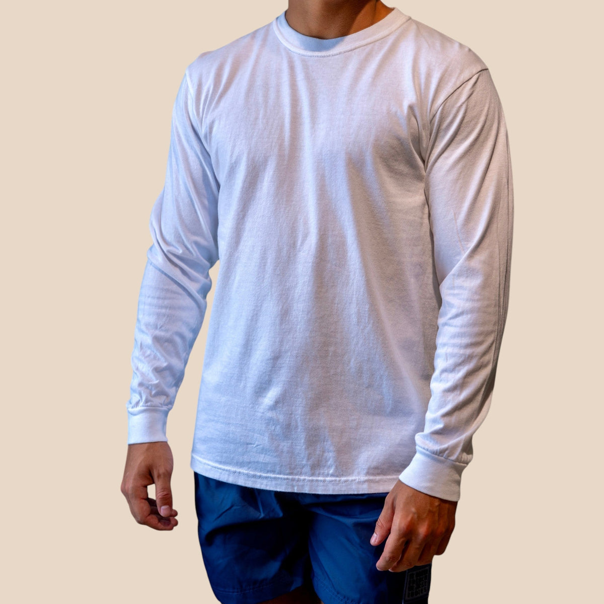 Homme portant un t-shirt à manches longues blanc St Barth French West Indies avec un short bleu