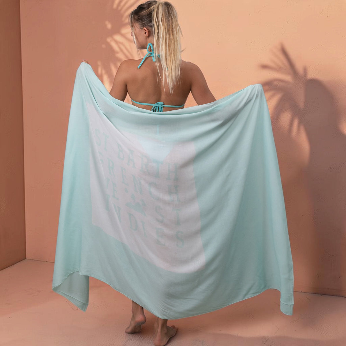 Femme portant un paréo St Barth French West Indies bleu clair en voile de rayonne doux avec logo imprimé