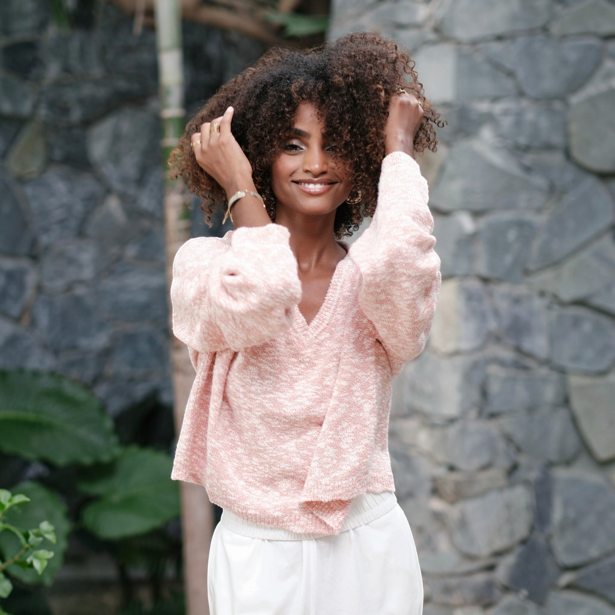 Modèle portant le pull court St Barth French West Indies rose à col en V en maille douce avec détails argentés