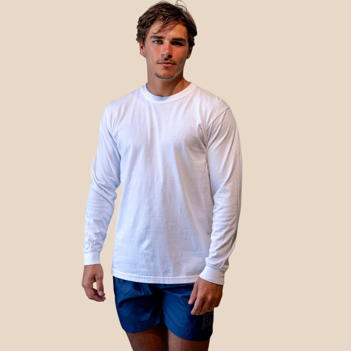 Homme portant un t-shirt blanc à manches longues St Barth French West Indies avec un short bleu