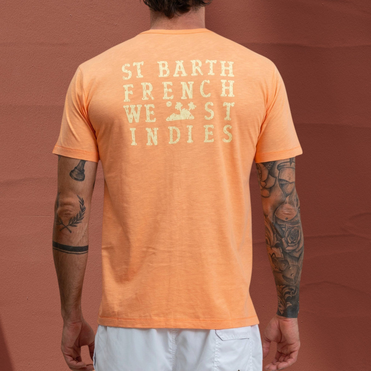 T-shirt Jasper St Barth French West Indies en coton slub orange avec logo imprimé au dos sur un homme tatoué