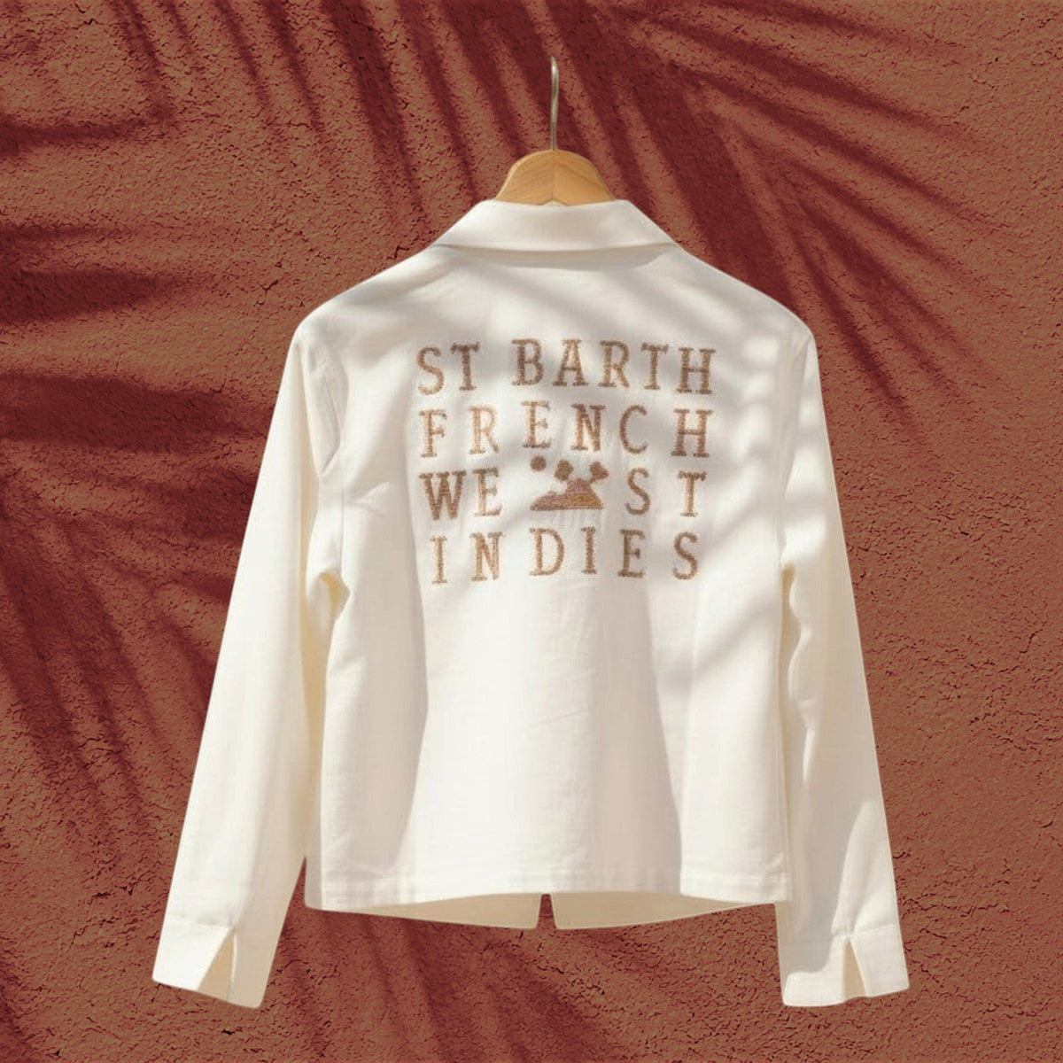 Veste chemise ROMY St Barth French West Indies blanche en tissu léger avec logo brodé au dos sur fond terracotta